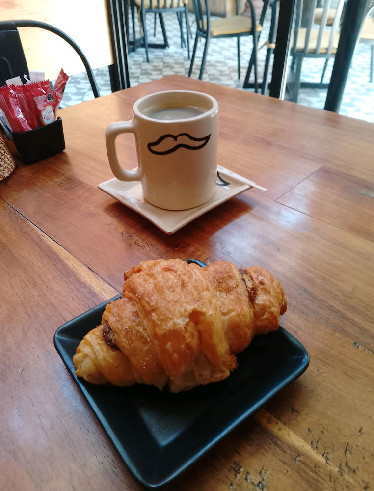Coffee with a moustache and croissant
